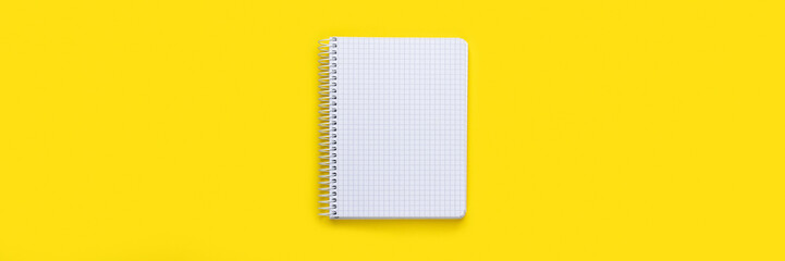 Open spiral squared notebook with blank empty white sheets on bright yellow background, top view...