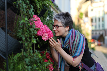 A mature woman, a florist by occupation, enjoys the beauty of nature, surrounded by flowers.