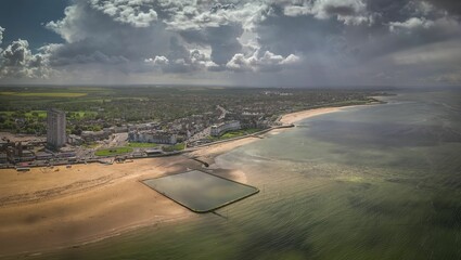 Aerial view of the cityscape and sandy beach surrounded by greenish waters. Margate, Kent, England