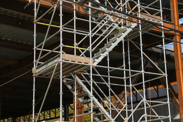 Construction site with workers, tools, and safety gear amidst yellow caution signs, showcasing industrial activity and safety protocols