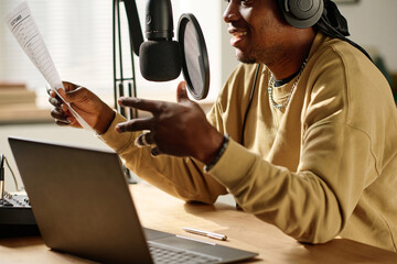 Focus on paper in hand of young African American male blogger or radio presenter reading text in...
