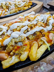 close up view of fully loaded fries with testy sauces and chicken