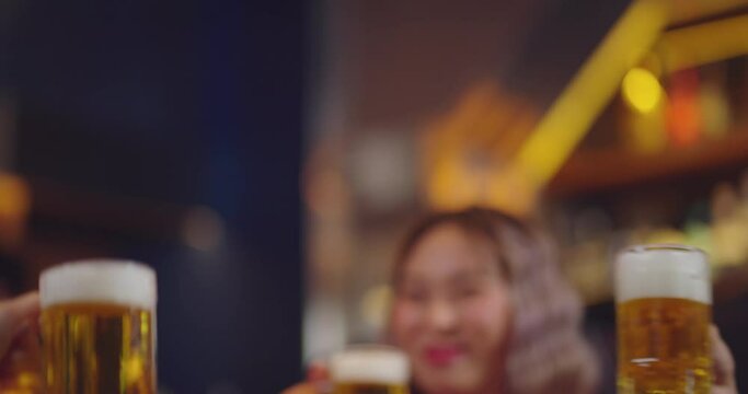 Close-up Group of People Holding Beer and Cheer in Restaurant. They Enjoying with Night Party Together. Party, Lifestyle, Happiness, Cheerful and Celebration Concept. 