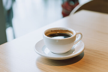 Cup of black coffee on a wooden table in a street cafe.