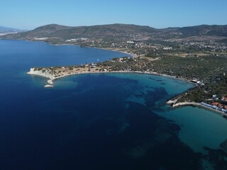 an island with blue water and mountains in the distance in a blue sky