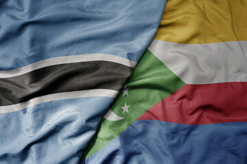 big waving national colorful flag of botswana and national flag of comoros .