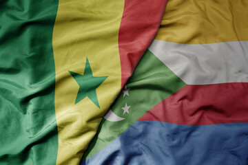big waving national colorful flag of senegal and national flag of comoros .