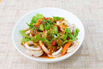 Squid salad cut into circles Thai style squid salad, sour, spicy, delicious. Squid salad on a white plate.