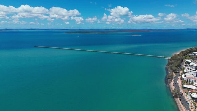 Aerial footage of Urangan pier and cars driving on Esplanade road in Urangan, QLD, Australia
