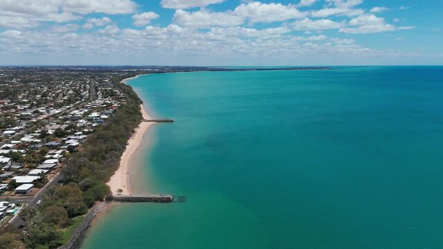 High drone footage of the stone piers on the sandy shore of Hervey Bay in Urangan, QLD, Australia