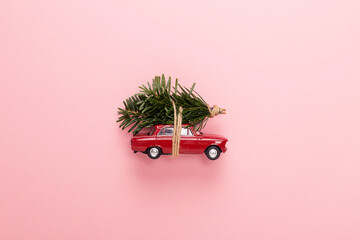 retro red toy car carrying green Christmas trees on top