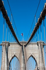 American flag on the Brooklyn Bridge with a clear blue sky in the background