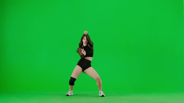 Framed on a green background, chromakey stands a young woman. She looks into the camera, wears outspoken clothes and demonstrates the Twirk dance. Shes sexy, plastic