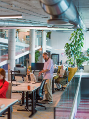 In a modern startup office, a diverse group of young professionals collaboratively tackles various...