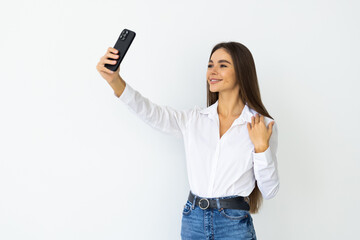 Fototapeta premium Portrait of a smiling woman taking selfie with phone isolated over white background