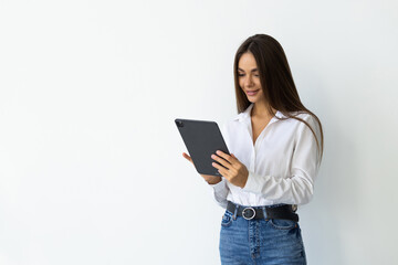Fototapeta premium Portrait of young smiling woman standing with tablet near concrete wall. Concept of planning.