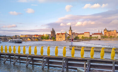 Museum Kampa's Yellow Pinguins, modern art in Prague, Czech Republic and view of old town with Charles Bridge on Vltava river in the background, at sunset