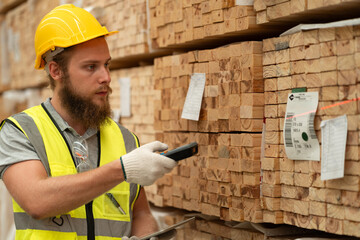Caucasian businessman checking stock timber with bar code scanner at wood factory 