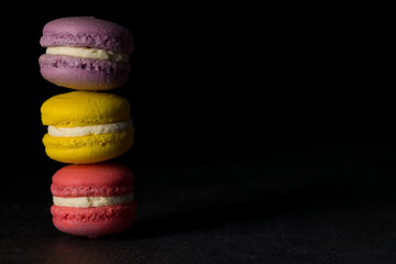 Colored macaroons. Colorful macaroons stacked in a pile on black background