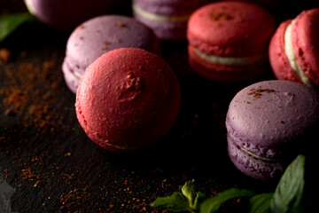 Colored macaroons. Delicious sweet colorful French desserts on black background