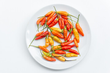 Red chili peppers. Red hot chili peppers on white plate isolated on white background. Colorful chili peppers. Spicy red chili peppers. Flat lay, top view.