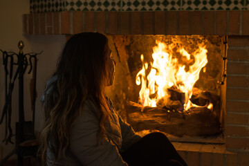 latina woman sitting in front of the fireplace in cold winter