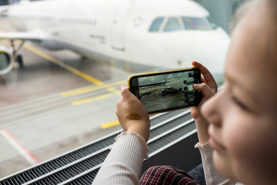 Child Photographing Airplane on the Tarmac Through a Smartphone