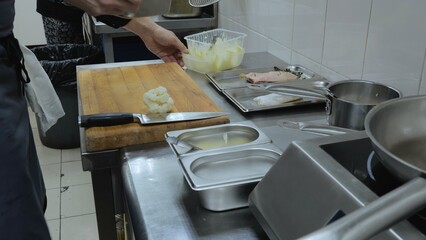 The cook cooks in the kitchen of the restaurant, the kitchen and kitchen utensils, the hands of the cook at work