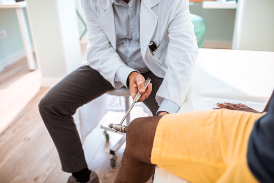 Doctor using a reflex hammer on his patient in the doctors office