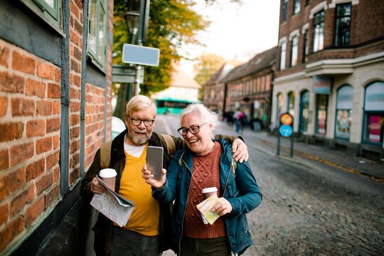 Senior couple holding smartphone on vacation in city