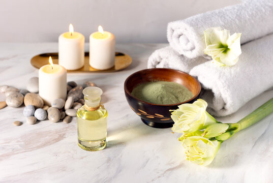 Beauty spa treatment with oil, laminaria algae in bowl and candles on light  background.