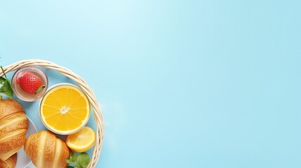 Summer breakfast with wicker basket, coffee, bun, strawberry and orange juice on a blue background. Flat lay style. Summer picnic. Empty space