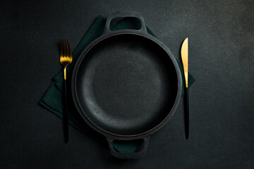 Metal pan with festive cutlery on the table. Free copy space. Top view On a dark background.