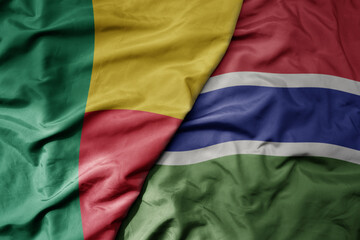 big waving national colorful flag of benin and national flag of gambia .