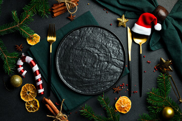 Festive Christmas table setting. A plate with festive cutlery on the table. Free copy space. Top view On a dark background. - obrazy, fototapety, plakaty