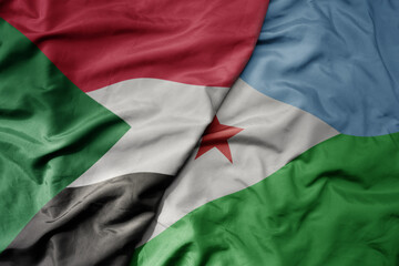 big waving national colorful flag of sudan and national flag of djibouti .