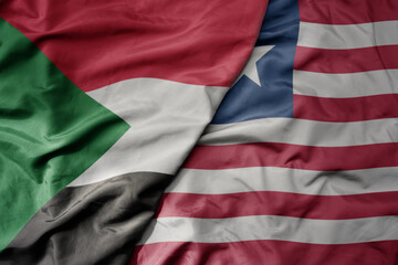 big waving national colorful flag of sudan and national flag of liberia .