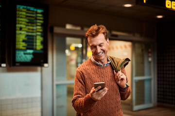 Happy Commuter Using Smartphone at Train Station - obrazy, fototapety, plakaty