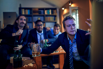 Young friends colleagues watching football,soccer,basketball,sports game on tv after work at home