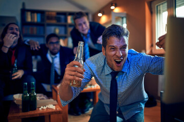 Young friends colleagues watching football,soccer,basketball,sports game on tv after work at home