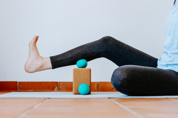 Woman doing calf muscle myofascial release with ball on cork block © Cristina