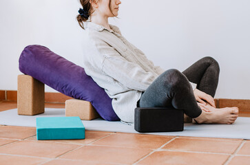 Woman preparing to do supported restorative yoga pose with props © Cristina
