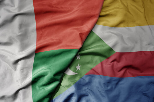 big waving national colorful flag of madagascar and national flag of comoros .