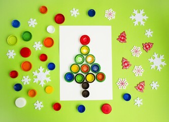 DIY Christmas crafts made from multi-colored plastic lids.  New Year tree with colored balls.  Flat laying.  Concept of children's creativity, Christmas and New Year holiday.