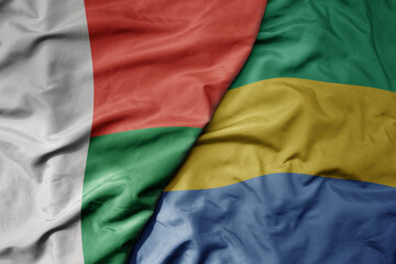 big waving national colorful flag of madagascar and national flag of gabon .