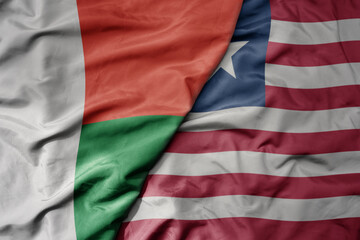 big waving national colorful flag of madagascar and national flag of liberia .