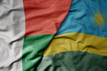big waving national colorful flag of madagascar and national flag of rwanda .