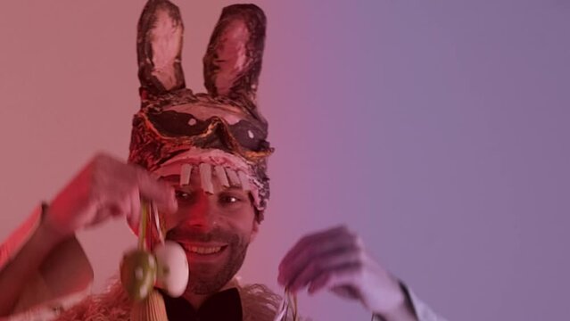 handsome Bunny Easter man, Happy attractive young guy in cringe rabbit monster mask holding Easter eggs, looking at camera, Happy holiday and funny easter day concept, Humor and Creative Celebration