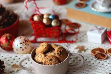 Various colorful Christmas decorations, soft blanket, cup of tea, sweet snacks and lit candles on the table. Cozy Christmas atmosphere at home. Selective focus.