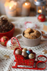 Various colorful Christmas decorations, soft blanket, cup of tea, sweet snacks and lit candles on the table. Cozy Christmas atmosphere at home. Selective focus.